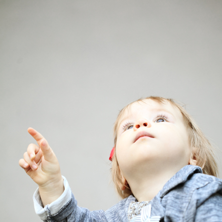 Cute child pointing and looking upの写真素材