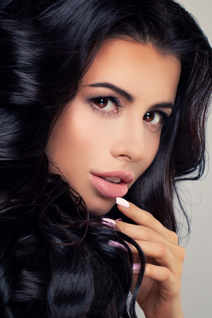 Perfect Brunette Woman with Dark Curly Hairstyle and Makeup. Cute Face Closeupの写真素材