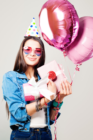 Pretty Girl with Gift Box. Holiday Portrait of Smiling Woman with Balloons and Giftsの写真素材