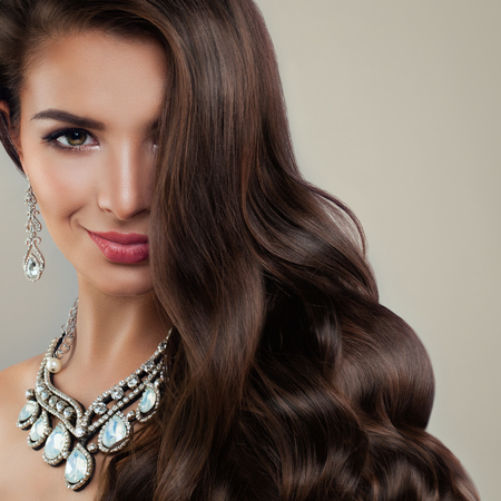 Perfect Woman Fashion Model with Diamond Earrings and Jewelry Necklaces. Beautiful Lady with Makeup and Curly Hairの写真素材