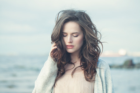 Portrait of a Beautiful Girl with Curly Hair on a Cold Windy Day Outdoorsの写真素材