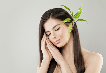 Beautiful Relaxing Woman with Green Bamboo Leaves on Head.の写真素材