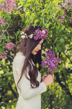 Beautiful female model with lilac flowers outdoorsの写真素材