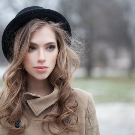 Attractive young woman with wavy hairstyle outdoors, portraitの写真素材