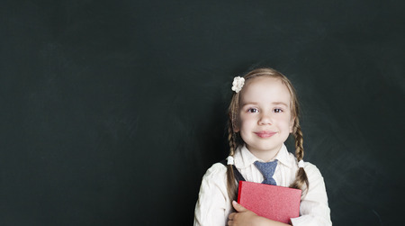 Cheerful smiling little girl on a green background. Back to school and education concept . Girl is...
