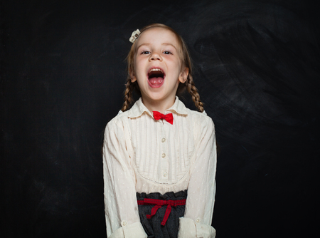 Happy Child Girl Laughing on Blackboard Background. Kid Creativity and Education Conceptの写真素材