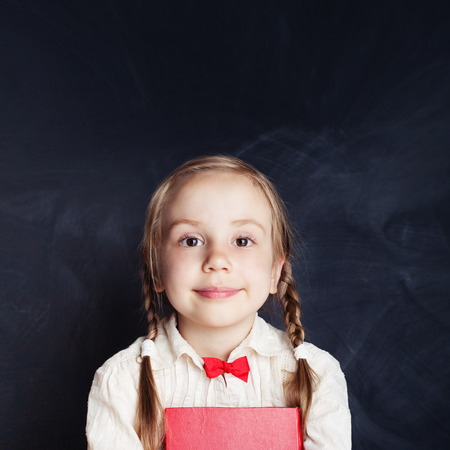 Cheerful little girl portrait. Beautiful child on empty blackboard background with copy spaceの写真素材