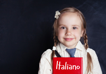 Smiling child student learning italian at the classroom chalkboard banner background with copy spaceの写真素材