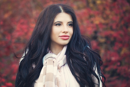 Beautiful autumn female model brunette with long wavy hair outdoorsの写真素材