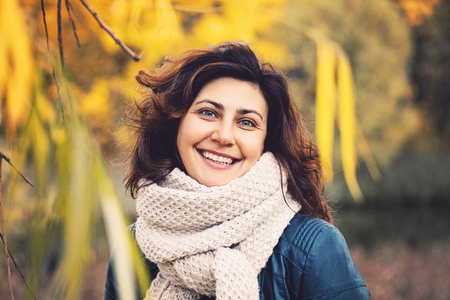 Autumn portrait of cute smiling woman outdoorsの写真素材