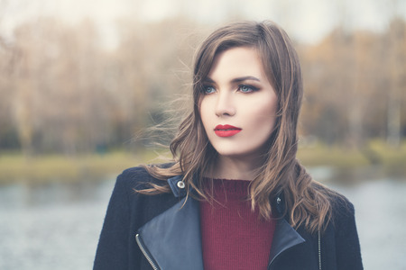 Romantic woman outdoor portrait. Perfect female model girl with blowing hair in cold autumn day