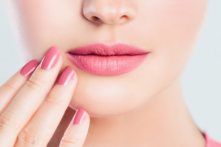 Perfect female lips closeup. Pink lips makeup and manicured nails with pink nail polishの写真素材