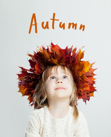Cute child girl with autumn leaves looking up, autumn conceptの写真素材