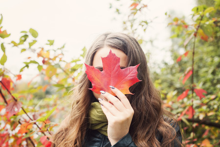 Beautiful woman holding fall leaf,  autumn conceptの写真素材