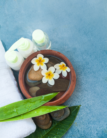 Spa or wellness setting with tropical flowers, bowl of water, towel and cream tube. Top viewの写真素材