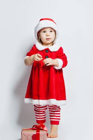 Christmas child girl in Santa hat with Christmas gift box on white backgroundの写真素材