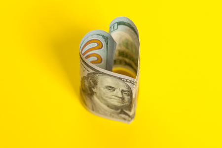 Heart of 100 US dollar note on yellow backgroundの写真素材