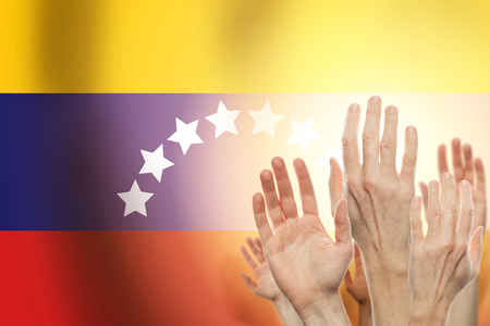 People raising hands and flag Venezuela on background. Patriotic conceptの写真素材