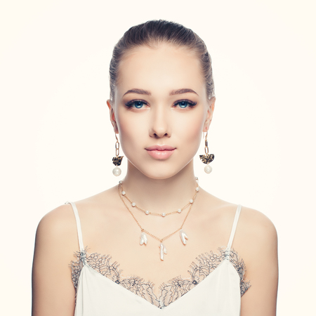 Beautiful young woman wearing fashion golden chain earrings and necklace with white pearls portraitの写真素材