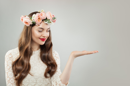Young Model Woman Holding Empty Open Palm Hand. Pretty Girl with Clear Skin, Curly Hair, Makeup and Flowers. Advertising Marketing and Product Placement Conceptの写真素材