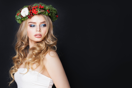 Pretty woman in green fir crown on black backgroundの写真素材