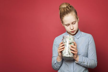 Saving money. Cute teen girl holding jar with money cashの写真素材