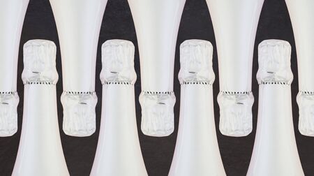 Row of white sparkling wine bottles on black backgroundの写真素材