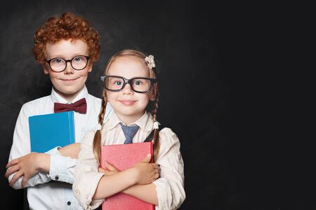 Happy kids pupils in glasses holding books on chalkboard backgroundの写真素材