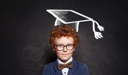 Successful schoolboy in glasses and graduation hat portraitの写真素材