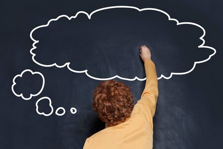 Child drawing empty speech clouds bubbles on chalkboard