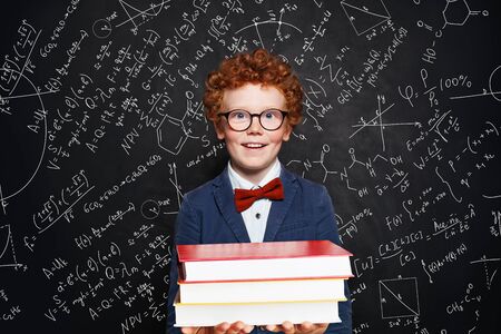 Clever kid boy in glasses holding book, portraitの写真素材