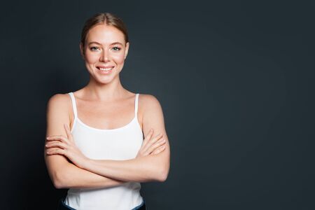 Happy woman with crossed arms on gray backgroundの写真素材