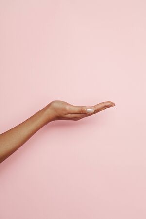 Empty woman hand on pink background. Woman hand presentingの写真素材