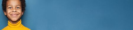 Happy black child face closeup on bright blue banner backgroundの写真素材