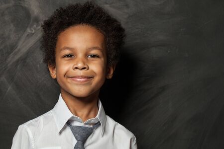 Happy kid boy on blackboard background. Smiling child face close up portrait