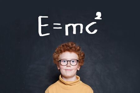 Curious kid boy wearing glasses on background with science formula