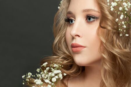 Young woman face close up. Blonde girl with perfect makeup and hairstyle on dark backgroundの写真素材
