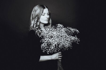 Black and white portrait of beautiful woman with white flowers on black backgroundの写真素材