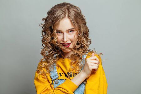 Cute girl with curly hairdo on white background. Positive emotionの写真素材