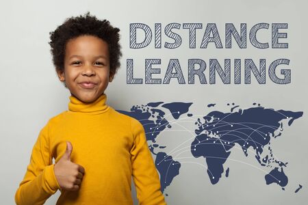 Distance learning concept with curious funny African American child boy on blackboard backgroundの写真素材