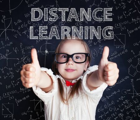 Happy little girl on blackboard background with math and art pattern. Distance learning and creativity education conceptの写真素材