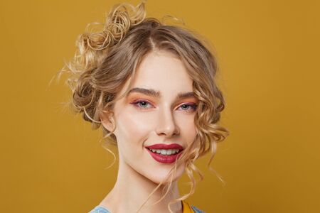 Young pretty woman with blonde hairdo on bright yellow background portraitの写真素材