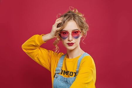 Pretty young woman in heart sunglasses on bright pink backgroundの写真素材