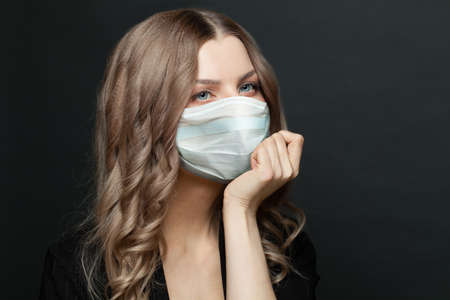 Pensive woman in protective mask on black background