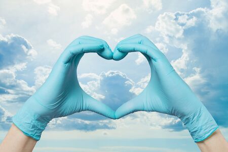Doctor hands making heart on sky clouds background. Save life conceptの写真素材