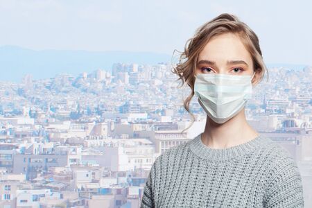 Young woman in protective mask on urban city background outdoorsの写真素材