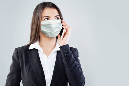 Woman in protective mask using smart phoneの写真素材