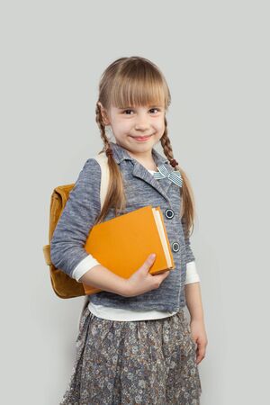 Cheerful child  girl with school bag and book. Back to school conceptの写真素材