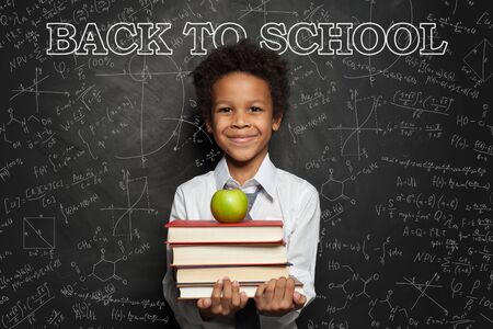 Smiling child in classroom on blackboard background with science formulasの写真素材