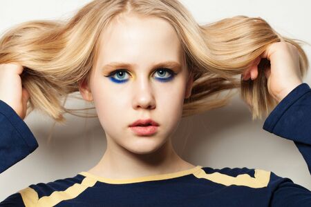 Young girl with makeup and blonde hair on white background